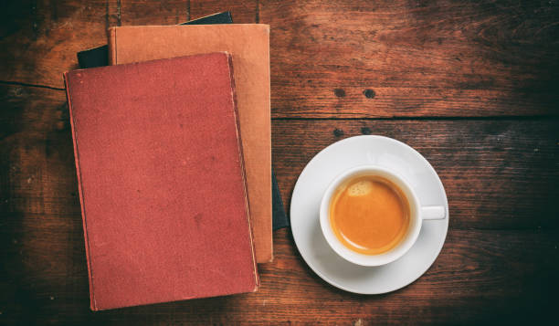 A cup of coffee with open notebook on wooden table.