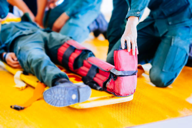 Two mountain rescuers putting splints on an injured male mountain climber/hiker's arm and leg on the mountain.