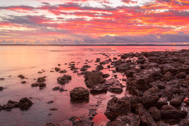 Vivid red sunrise on the coast in Australia Rich red sunrise from the rockshelf at a small coastal township called Callala Bay a tranquil setting and suitable mooring for boats and yachts too. shoalhaven photos stock pictures, royalty-free photos & images