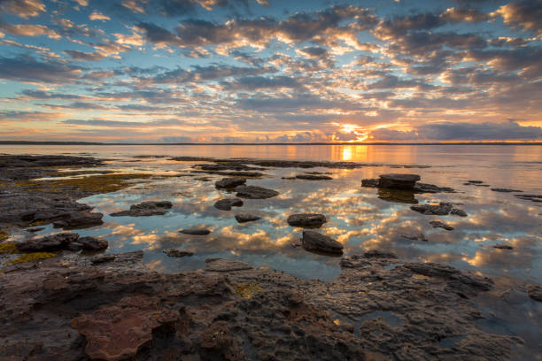 joli lever du soleil et les reflets dans l’eau avec des roches de premier plan - downunder photos et images de collection