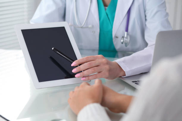 istock Doctor and patient, close-up.  Physician pointing into touch pad screen of tablet computer. Medicine, healthcare and helping concep 983146992