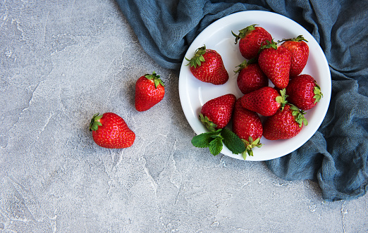 Plate with fresh strawberries on a stone background