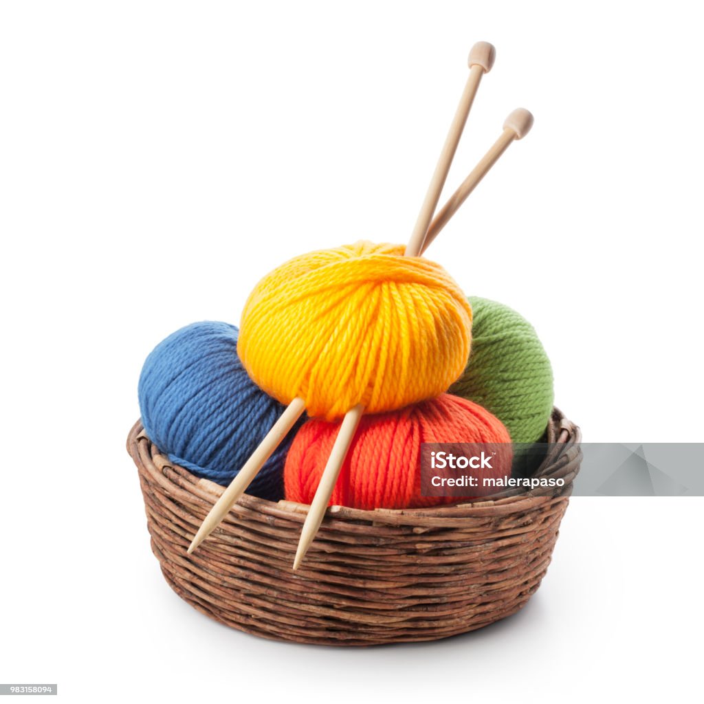 Colored balls of wool with knitting needles in basket Colored balls of yarn with knitting needles in basket on white background. Knitting Stock Photo