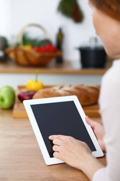 istock Woman cooks at the kitchen using tablet computer. Copy space area at touch pad. Healthy meal, vegetarian food and lifestyle concepts 983174232