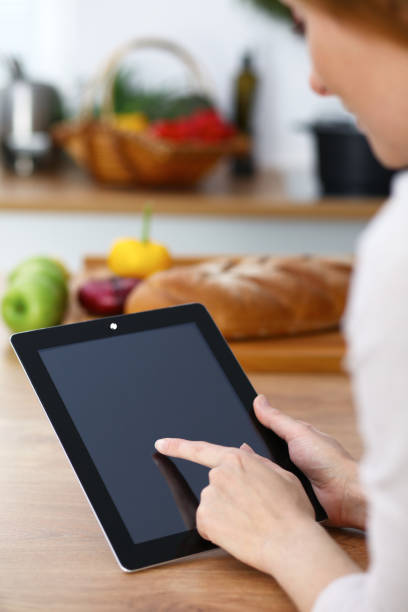 istock Woman cooks at the kitchen using tablet computer. Copy space area at touch pad. Healthy meal, vegetarian food and lifestyle concepts 983176122