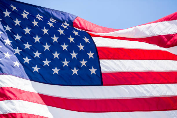 istock American flag flying in the wind blue sky background 983177452