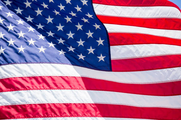 istock American flag flying in the wind blue sky background 983179638