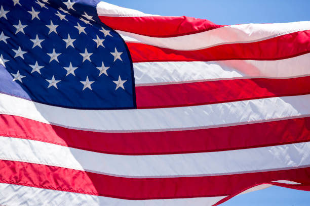istock American flag flying in the wind blue sky background 983182996