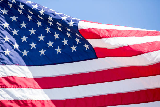 istock American flag flying in the wind blue sky background 983185240