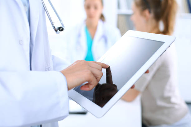 istock Doctor using tablet computer, close-up of hands at touch pad screen 983192956