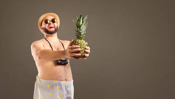 istock Funny overweight  man with a pineapple on vacatio 983195538