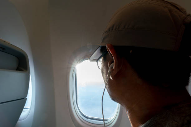 istock man sitting beside airplane window, looking out 983204390