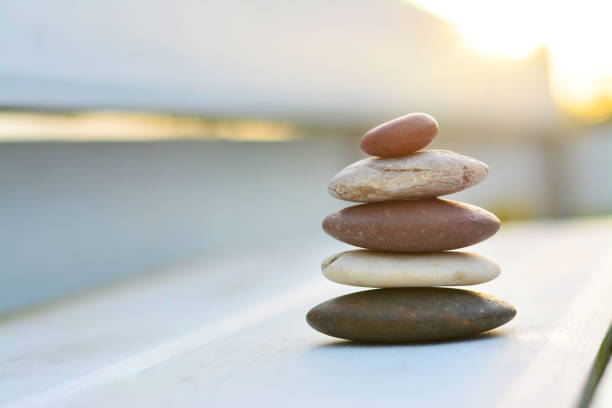 istock Zen stones on white wooden floor with sunset background left space position. 983214692