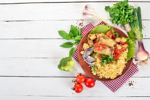 Bulgur with meat, paprika, cherry tomatoes, and vegetables. On a wooden background. Top view. Copy space.