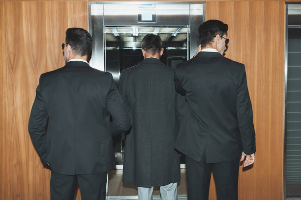 istock back view of bodyguards and businessman standing at elevator 983219634