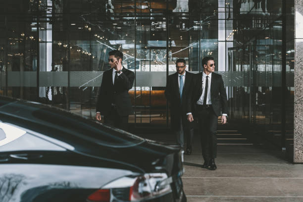 istock businessman and two bodyguards walking to auto 983229176