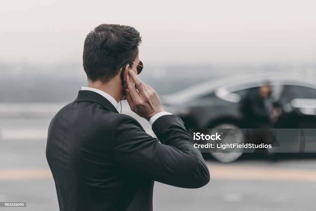 handsome bodyguard standing and listening message with security earpiece on helipad Bodyguard Stock Photo