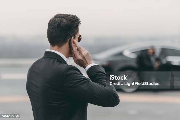 Handsome Bodyguard Standing And Listening Message With Security Earpiece On Helipad Stock Photo - Download Image Now