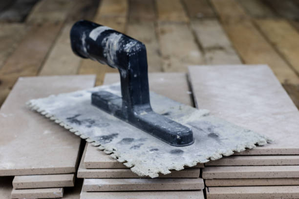 istock Tiles for laying on the floor. Accessories and material for a construction worker arranged on a wooden workshop table. Dark background 983237212