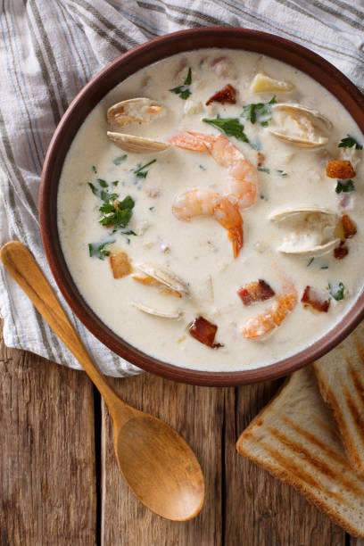 istock American food: New England clam chowder soup close-up on a in a bowl. Vertical top view 983239632