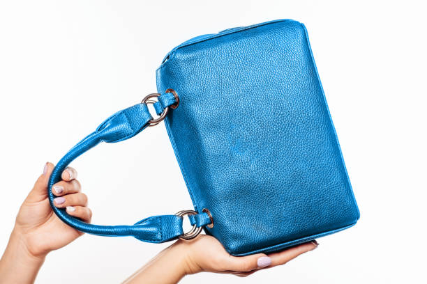 istock female hand holding blue bag isolated 983263636