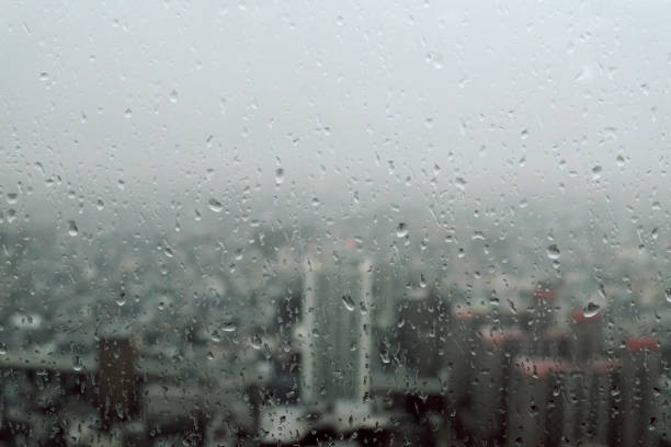 istock Cityscape through a glass window with raindrops in skyscrapers 983277504