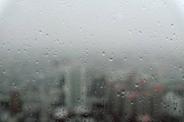 istock Cityscape through a glass window with raindrops in skyscrapers 983277510