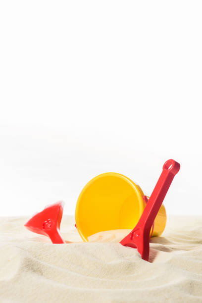 Bucket and beach toys in sand isolated on white