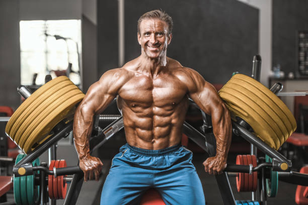 istock Brutal aged strong bodybuilder athletic men pumping up muscles with dumbbells 983298712