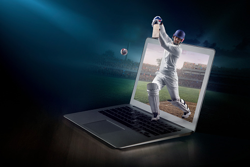 Cricket on laptop. Live broadcast. Laptop on the table with cricket player that came to life. Cricket player beats the ball