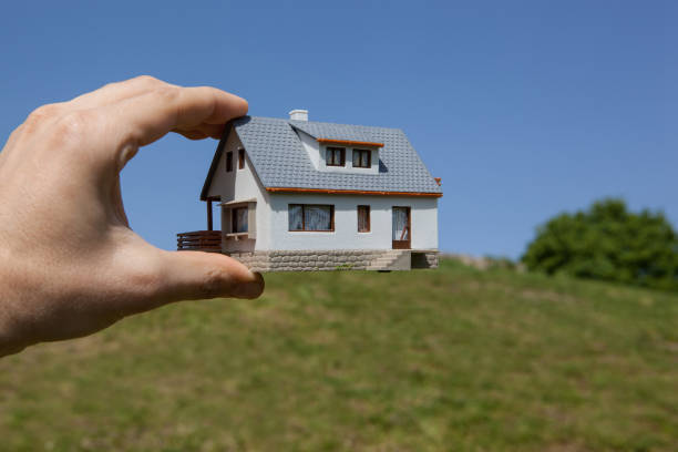 Rêve d’avoir une maison. Main tenant une maison modèle champ vert - Photo