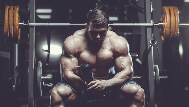 istock Brutal strong bodybuilder athletic men pumping up muscles with dumbbells 983336496