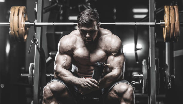 istock Brutal strong bodybuilder athletic men pumping up muscles with dumbbells 983337262