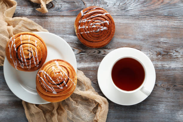 istock Cinnamon buns with cup of tea on wooden table 983340240