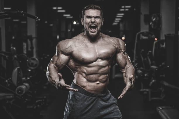 istock Brutal strong bodybuilder athletic men pumping up muscles with dumbbells 983342944