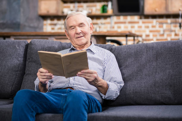 家で本を読んで素敵な年配の男性 - senior adult relaxation sofa reading ストックフォトと画像