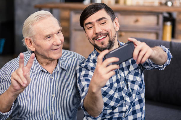 istock Joyful aged man making selfies with his son 983350122
