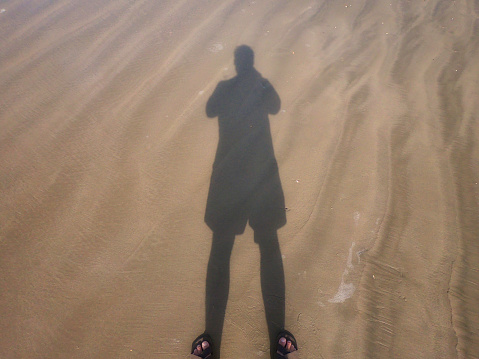 Shadow of a man projected on the sand of a beach