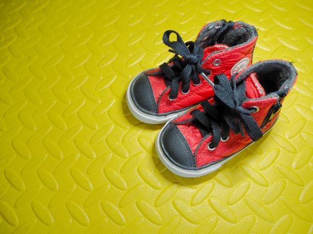 istock Baby shoes on yellow rubber floor. 983366962