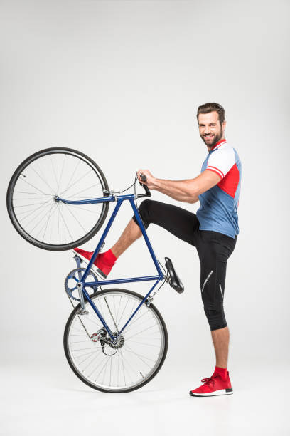 istock handsome smiling sportsman posing with bicycle, isolated on white 983377300