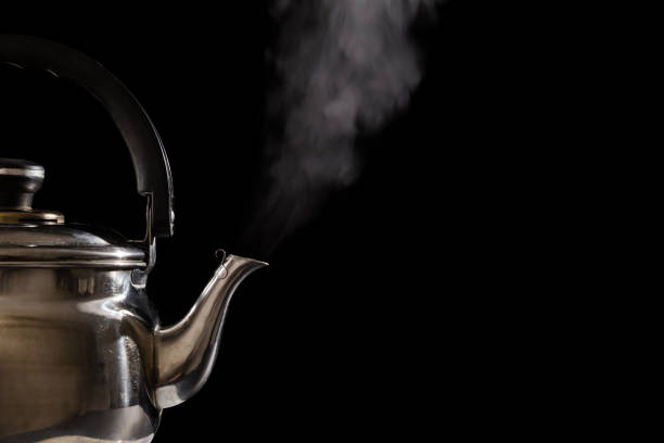 istock Closeup of steam from boiling teapot on black background 983377886