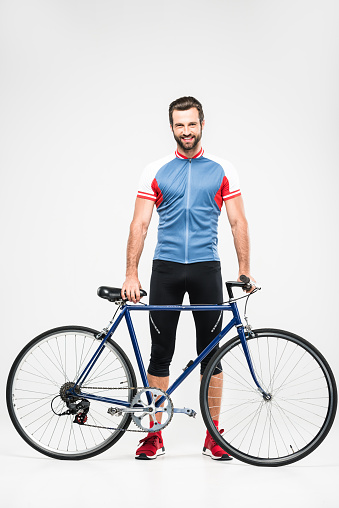 handsome cheerful cyclist in sportswear posing with bike, isolated on white