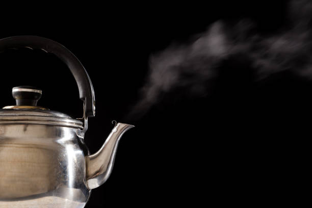 istock Steam from boiling teapot on black background 983392406
