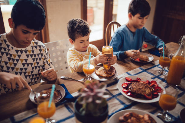 istock Brothers eating pancakes for breakfast sitting around kitchen table 983410768