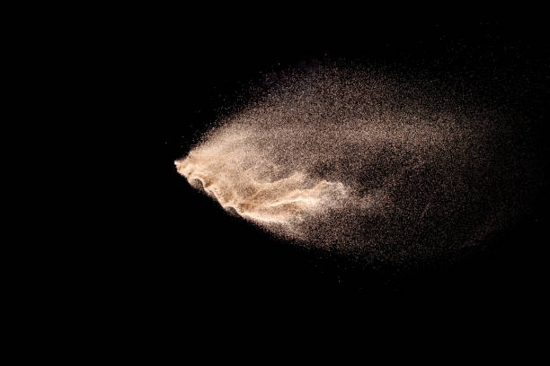 istock Abstract sand cloud. Golden colored sand splash agianst dark background. Yellow sand fly wave in the air. Sand explode on black background ,throwing freeze stop motion. 983412038