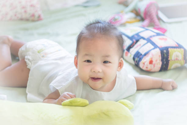 istock infant baby lying down on the bed and smiling 983418266