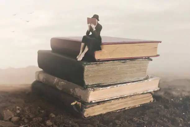 Photo of Surreal image of a woman reading sitting on top of a book