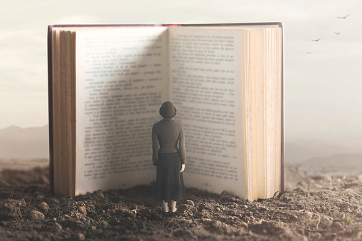 momento surrealista de una pequeña mujer leyendo un libro gigante en una tierra desértica photo