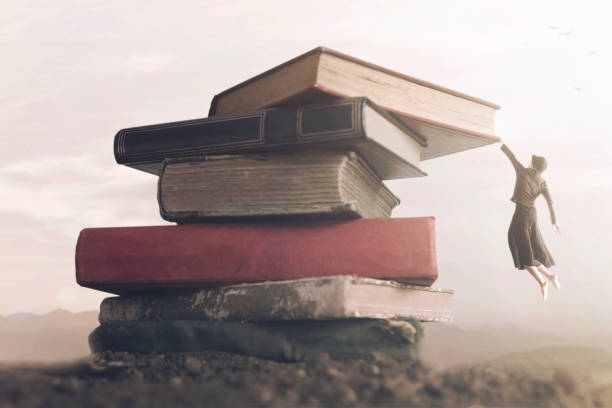 conceptual image a brave woman climbing a pile of books to reach the top stock photo