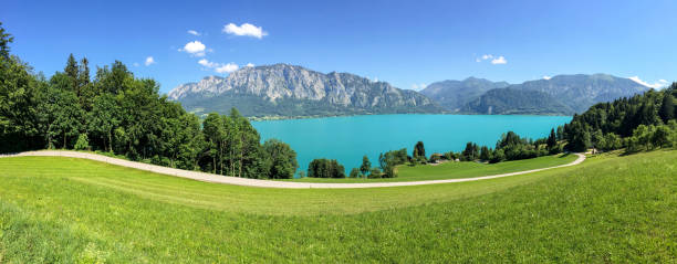 View to lake Attersee with green pasture meadows and Alps mountain range near Nussdorf Salzburg, Austria View to lake Attersee with green pasture meadows and Alps mountain range near Nussdorf Salzburg, Austria attersee stock pictures, royalty-free photos & images
